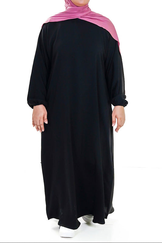Person wearing a black affordable abaya with a pink hijab on a white background