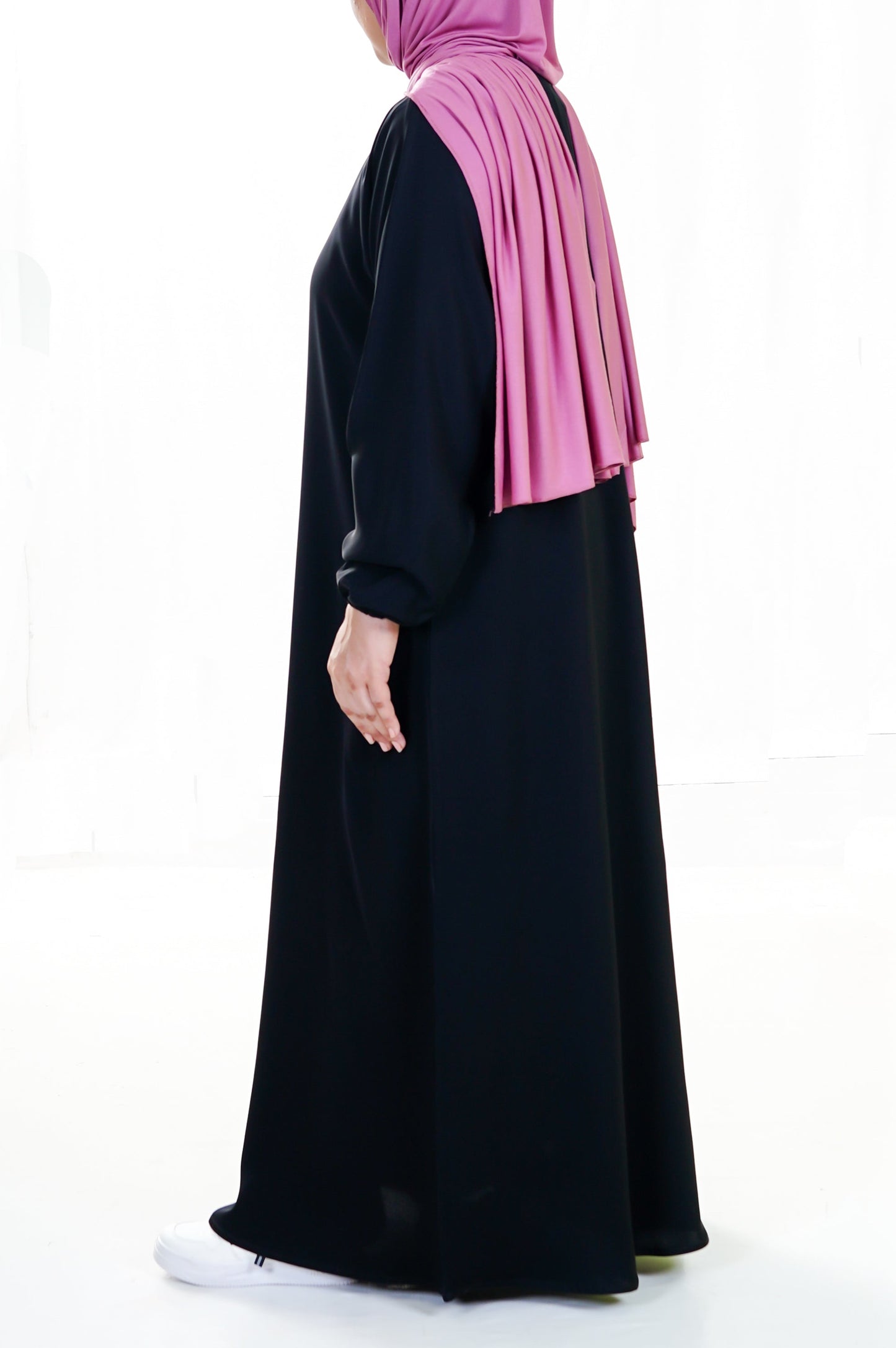 Person wearing a black abaya and pink hijab on a white background