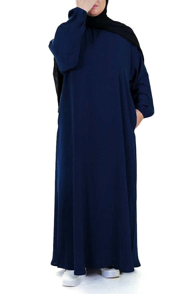 Person wearing a navy blue abaya with a black hijab on a white background