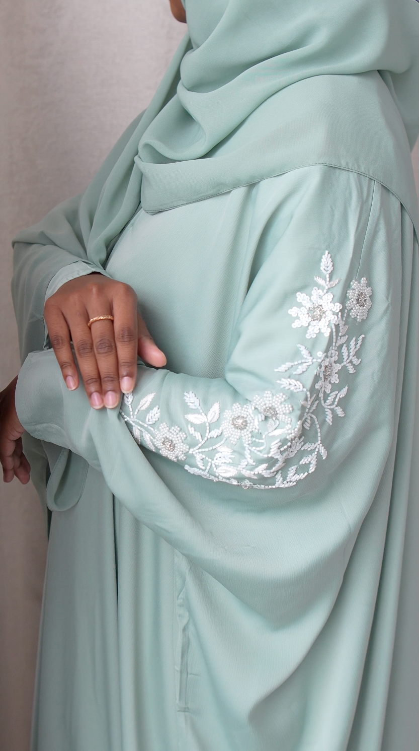 Light blue abaya with floral embroidery on sleeves against a neutral background
