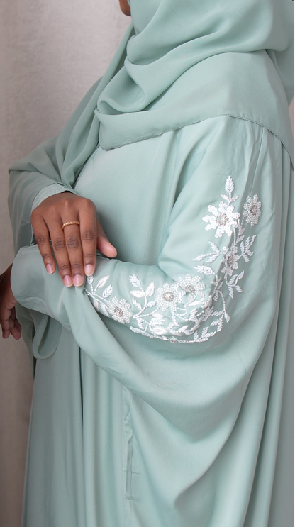 Light blue abaya with floral embroidery on sleeves against a neutral background