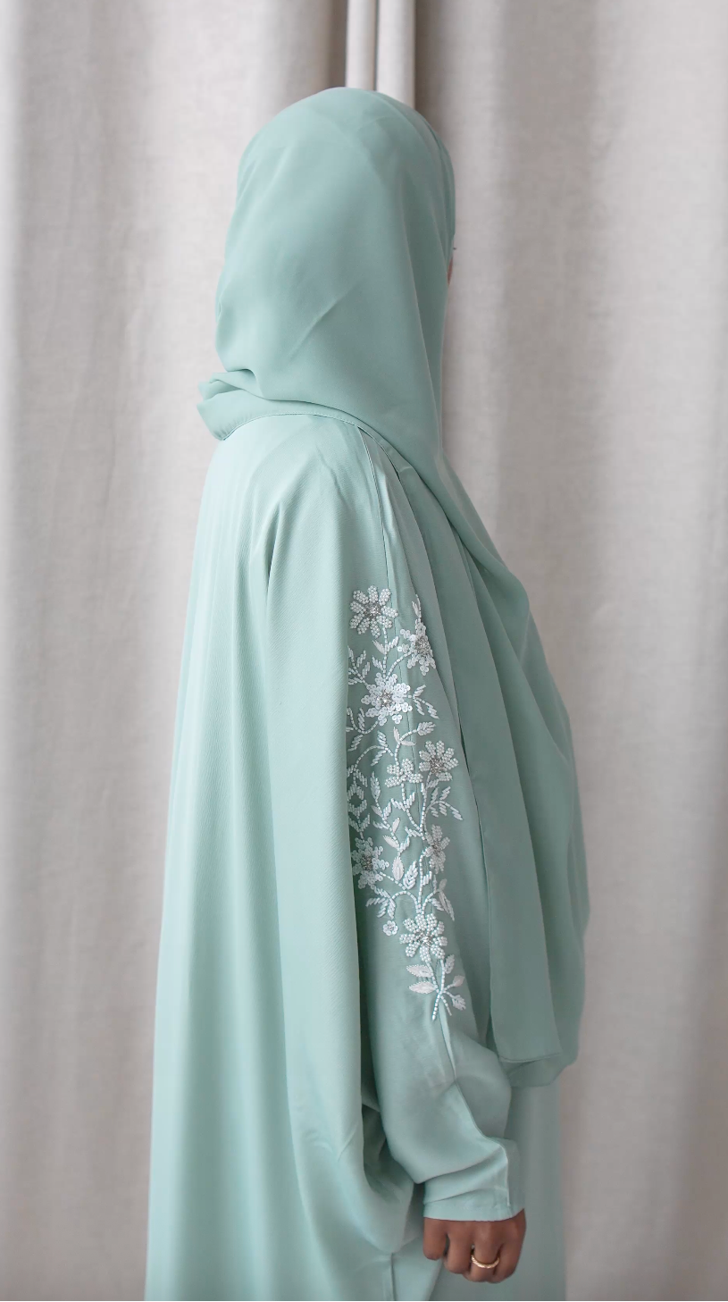 Light blue abaya with floral embroidery on a plain background